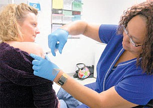 Hixson resident Donna Wilson, left, receives immunization shots for typhoid and hepatitis A and B from LPN Denise Morris at the Chattanooga-Hamilton County Health Department. Ms. Morris said that 85 percent of the vaccines she distributes to adults are for overseas travel.