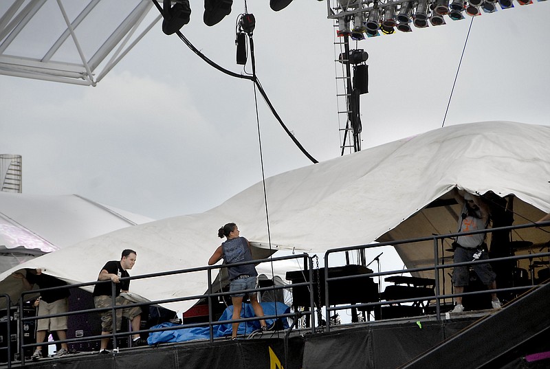 Staff photo by Matt Fields-Johnson/Chattanooga Times Free Press 
The stage crew covers the Coca-Cola Stage for inclement weather as thunderstorms roll in Tuesday at the Riverbend Festival.