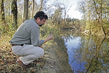 Staff Photo by Jake Daniels/Chattanooga Times Free Press
Troy Keith with TDEC examines some soil from the side of Chattanooga Creek. The creek has been shored up with a temporary fix to stop creosote from seeping into the water, but Keith says it is just temporary.