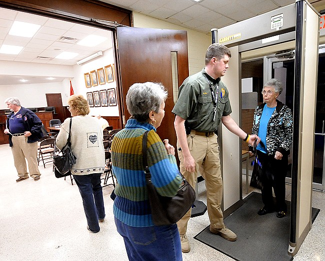 Staff Photo by Tim Barber/Chattanooga Times Free Press 
Red Bank Police Detective Michael Ray assists Charlotte Thompson, right, through a metal detector before Tuesday's commission meeting at Red Bank City Hall. Her friend Jane Helton, center, waits for the process. Red Bank is the only city in Hamilton County using a metal detector to screen people who come to city meetings.