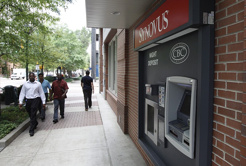 Pedestrians walk past a Synovus ATM off Market Street in Chattanooga.