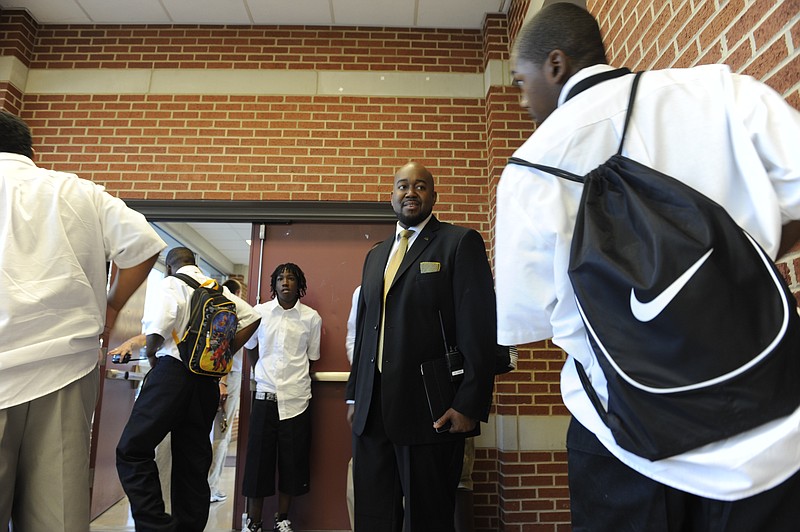 Paul Smith, principal of Howard High School, greets students as they enter the building on the first day of school on Wednesday. As students entered the cafeteria and gymnasium, staff of the school checked for white, tucked-in shirts and ties for each student. Students who did not meet dress code were asked to correct the issue before they could enter the school.