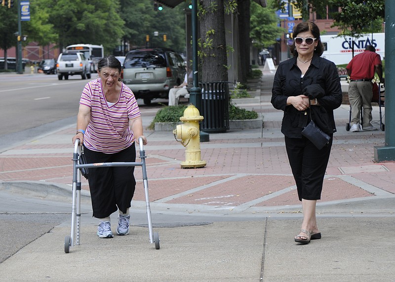 Nancy Rus, right, and Mary Cody cross 10th Street on their way to the Pickle Barrel, where Cody wants to thank employees for being kind to her while she stayed on a park bench outside of the business.