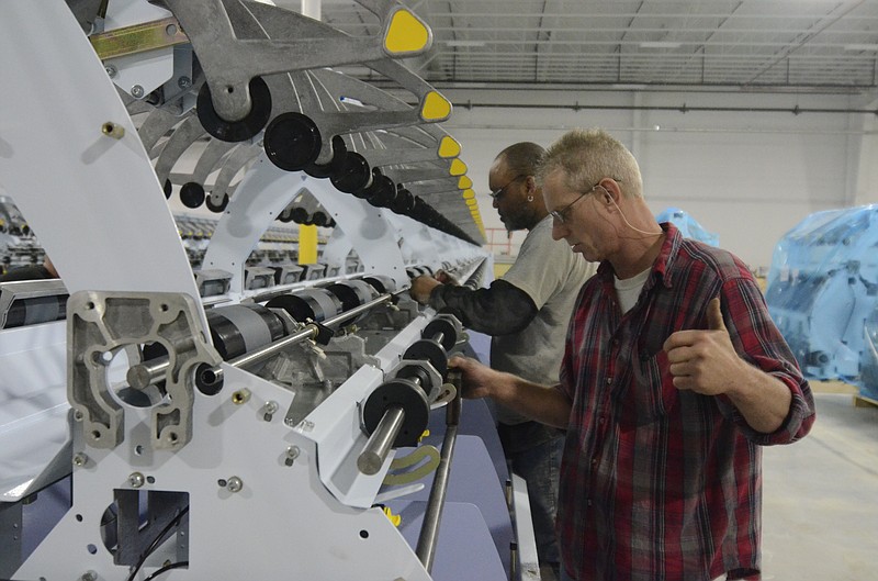 Steve Livingston, right, and Marvinces Sanders line level a twister machine in a new Engineered Floors  facility in Dalton.