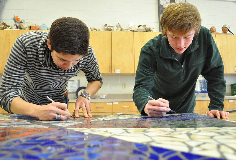 LaFayette High School students Jayro Benitez, left, and C.J. Pledger, scrape grout from between the tiles of a mosaic Friday afternoon in the art room. Both students helped with the construction of the mosaic, which is going to be placed in the terminal of Barwick-LaFayette Airport.