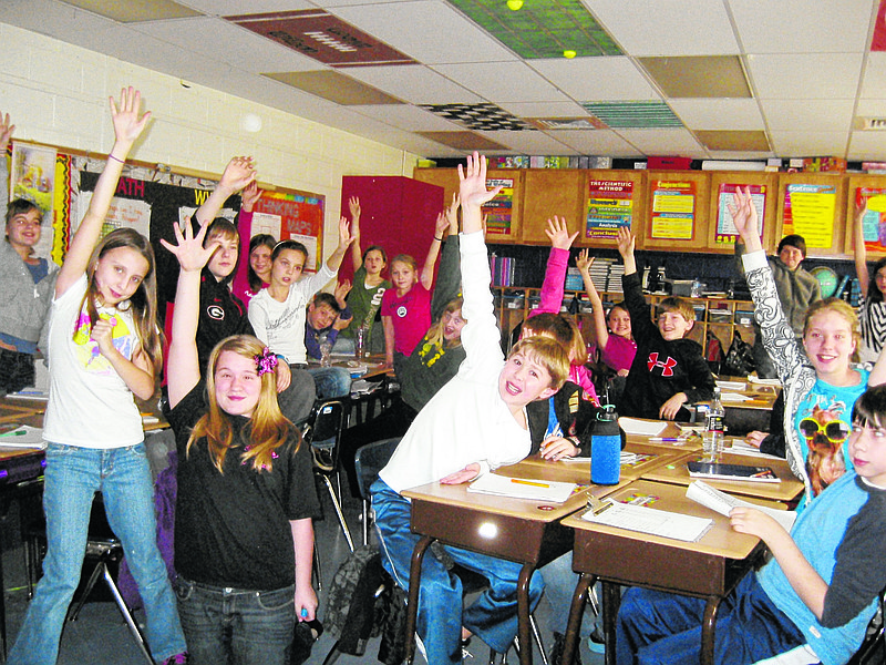 Boynton Elementary School fifth-grade students raise their hands hoping teacher Blake O'Keefe will call on them. O'Keefe said students all want to answer questions so they can use the new Smart Board designed for interactive learning.