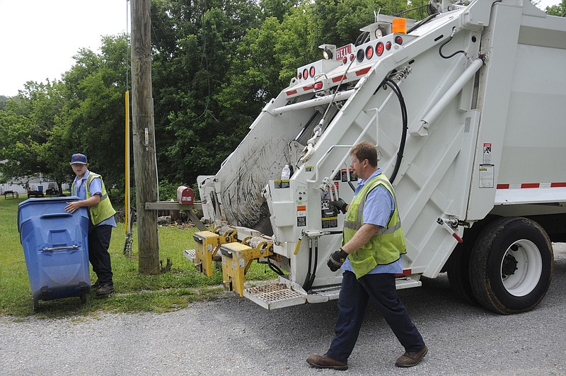 Bruce Hudson, left, and David Sneed work their garbage collection job Wednesday in Red Bank.