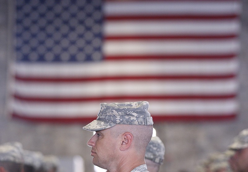 A soldier stands in formation in front of the American flag during a deployment ceremony at the Tennessee National Guard Headquarters in Chattanooga, Tenn.