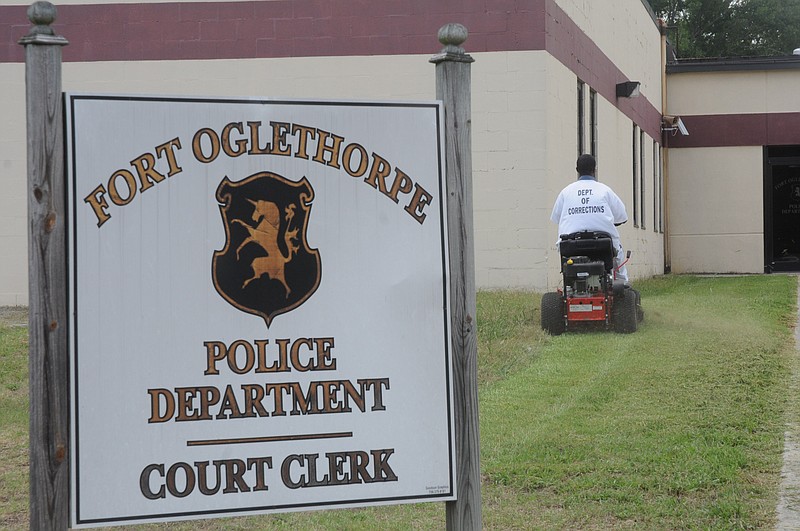 A Walker State prisoner works to cut the grass at the Fort Oglethorpe Police Department on Tuesday.