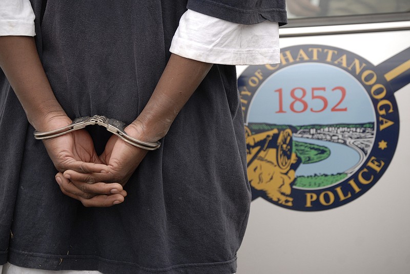 A man waits in handcuffs to discover if there is a warrant out for his arrest in this 2010 file photo. He was detained by the Chattanooga Police Crime Suppression Unit, which focuses on high-crime areas and gang-related incidents.