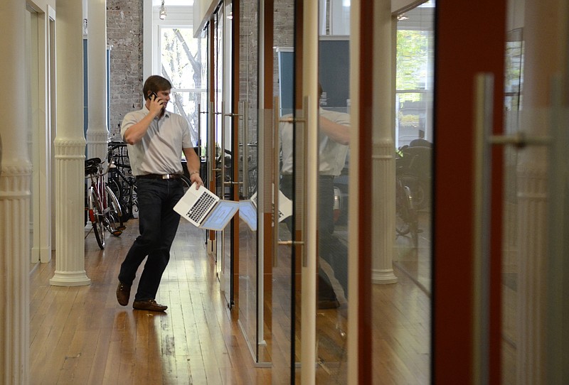Cameron Doody of Campus Bellhops walks into a cubicle to take a phone call at the Lamp Post Group offices in the Loveman's building in downtown Chattanooga. The Lamp Post Group provides support and helps with funding for entrepreneurs.