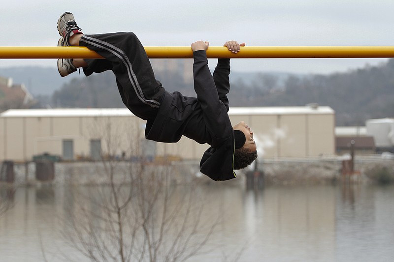 Aydian Lyle, 7, hangs from a pole at the PlayCore Riverfront Playground.