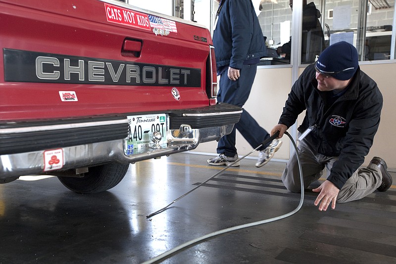 Emissions tester Mark Johnson searches for a tailpipe on a Chevrolet S10 truck Wednesday at the vehicle emissions testing facility on Riverfront Parkway in Chattanooga. The Tennessee Legislature is considering a bill that would exempt vehicles less than three years old from emissions tests.