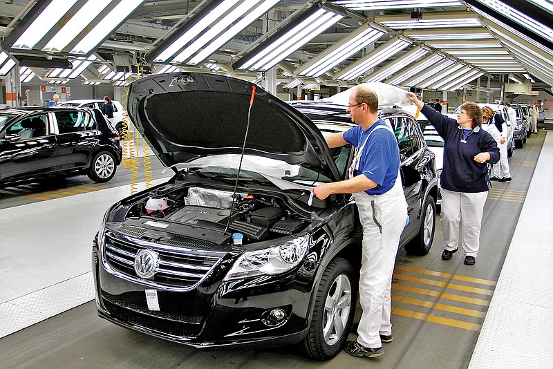 A worker wraps a protective liner around a Volkswagen Tiguan at quality control portion of the production line at the Volkswagen plant in Wolfsburg, Germany.