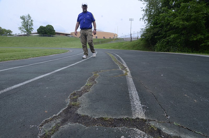 Coach Steven Lewis walks near cracks in the track at Central High School.