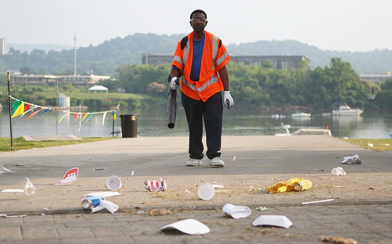 Timothy Wright blows trash onto Riverfront Parkway with a leaf blower, where a street sweeper will pick it up, on Sunday after the 2013 Riverbend Festival. Wright was volunteering his last day.