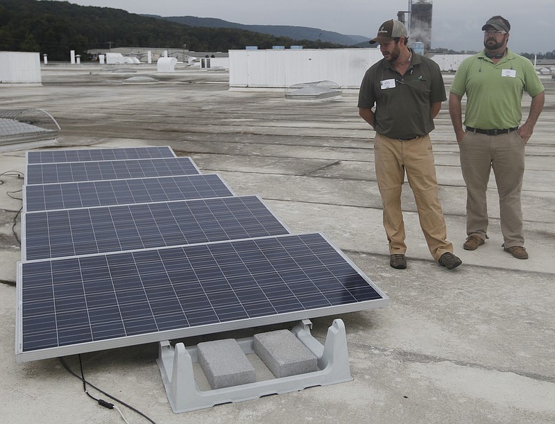 Fred Holder, left, and D.J. Shelton, with the company Greenform, stand next to an array of solar panels on the roof of the La-Z-Boy furniture factory in Dayton, Tenn. The factory has taken steps to become more environmentally friendly which include installing a starter array of solar panels on the roof and using battery-operated power tools and energy efficient lighting on a manufacturing pod.