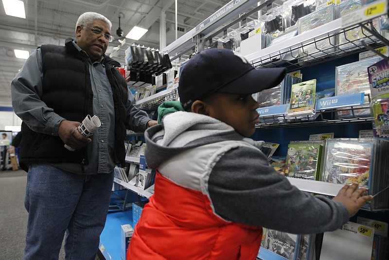 Chandler DeSouza, 5, right, looks through a section of educational games with his grandfather Hector while shopping Thursday at Best Buy on Gunbarrel Road in Chattanooga. The day after Christmas is typically one of the biggest shopping days of the year.