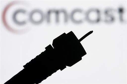 A silhouetted coaxial cable is photographed with the Comcast Corp. logo in the background in Philadelphia in this file photo illustration.