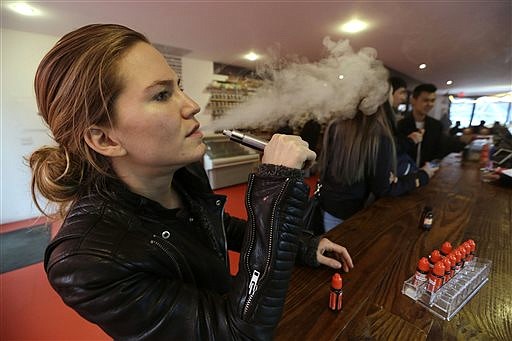 Talia Eisenberg, co-founder of the Henley Vaporium, uses her vaping device in New York in this Feb. 20, 2014, photo. Soon, the Food and Drug Administration will propose rules for e-cigarettes.