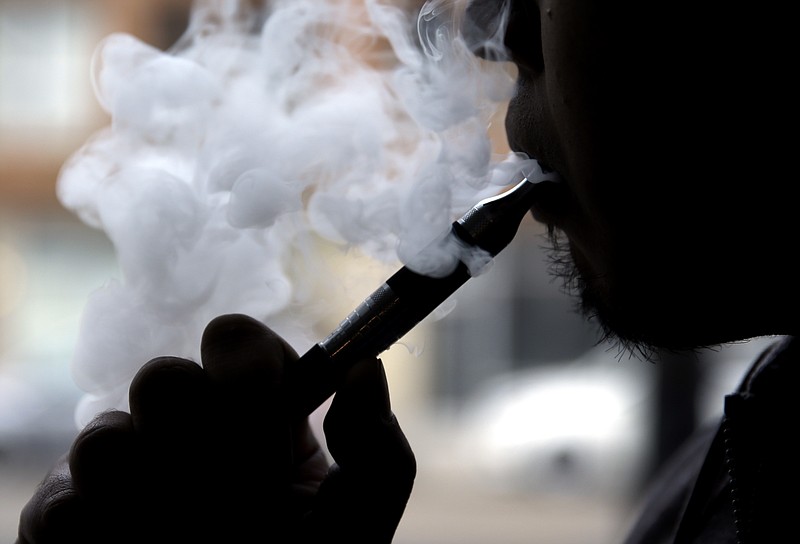 Daryl Cura demonstrates an e-cigarette at Vape store in Chicago, Wednesday, April 23, 2014. The federal government wants to ban sales of electronic cigarettes to minors and require approval for new products and health warning labels under regulations being proposed by the Food and Drug Administration.