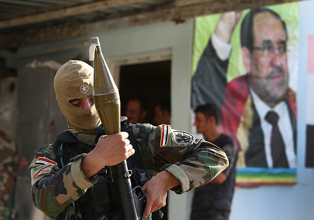 
              An Iraqi Shiite Turkmen gunman holds his RPG  as he stands in front of a portrait of Iraqi Prime Minister Nouri al-Maliki, right, at the front line village of Taza Khormato, in the northern oil rich province of Kirkuk, Iraq, Friday June 20, 2014. Thousands of people fled the town of Taza Khormato fearing the advance of Sunni insurgents who overran the neighboring village of Kirkuk. Taza Khormato residents said insurgents led by the al-Qaida inspired Islamic State in Iraq and the Levant seized the nearby village of Basheer, shelling and burning down the houses. Both communities are dominated by ethnic Turkmen Shiites who are seen as heretics worthy of death by Sunni extremists. (AP Photo/Hussein Malla)
            