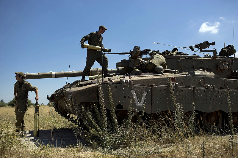 
              Israeli soldiers load shells in their tank following the first death on the Israeli side of the Golan since the Syrian civil war erupted more than three years ago, near the Israeli village of Alonei Habashan, in the area of Tel Hazeka, close to the Quneitra border crossing in the Israeli-controlled Golan Heights, Sunday, June 22, 2014. A civilian vehicle in the Golan Heights was targeted by forces in neighboring Syria on Sunday in an attack that killed a 15-year-old boy and prompted Israeli tanks to retaliate by firing on Syrian government targets, the Israeli military said. (AP Photo/Oded Balilty)
            