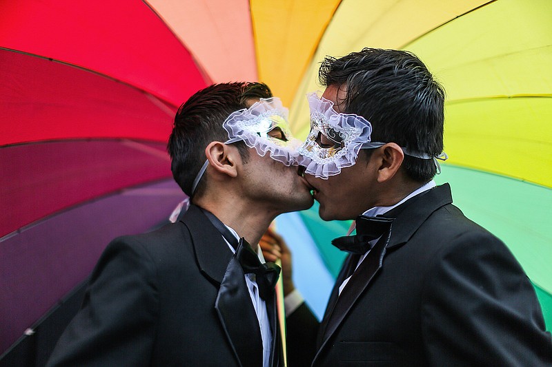 
              Men kiss under a rainbow umbrella during a gay pride parade in Lima, Peru, Saturday, June 28, 2014. Gays, lesbians and transgenders are holding gay pride parades worldwide this month as part of annual demonstrations demanding equal rights and to protest discrimination. (AP Photo/Sebastian Castaneda)
            