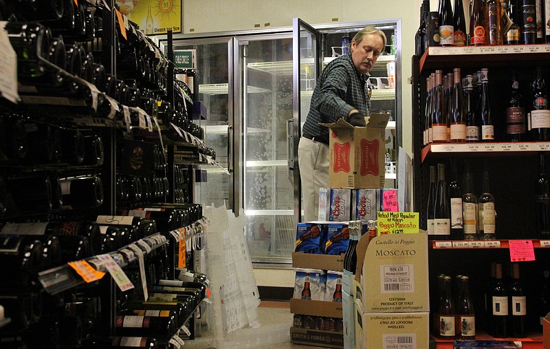 Bob Monroe, general sales manager for Carter Distributing Co., unpacks and shelves beer at Riley's Wine & Spirits on Tuesday, the first day that liquor stores can sell other goods besides liquor, wine and high gravity beer.