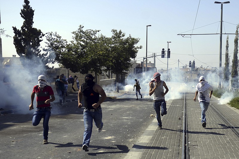 
              Palestinians run away from tear gas as they clash with Israeli security forces during the funeral of 16-year-old Mohammed Abu Khdeir in Jerusalem on Friday, July 4, 2014. Israeli police clashed with Palestinian protesters in Jerusalem on Friday as thousands of people converged on a cemetery for the burial of an Arab teenager, who Palestinians say was killed by Israeli extremists in a suspected revenge attack. (AP Photo/Mahmoud Illean)
            