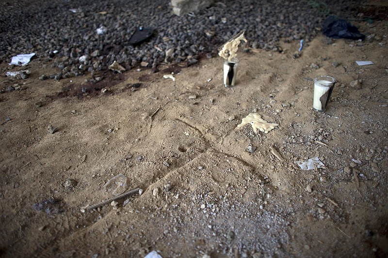 
              In this Thursday, July 3, 2014 photo, a cross and candles left by relatives of the dead mark the ground near bloodstains in an unfinished warehouse that was the site of a shootout between Mexican soldiers and alleged criminals on the outskirts of the village of San Pedro Limon, in Mexico state, Mexico. Mexico’s Defense Department says soldiers were patrolling in one of the most violent, lawless corners of the country on June 30 when they came under fire from a warehouse where a gang of 21 men and one woman were hiding. Mexico's military says one soldier was wounded, and all 22 suspects were killed. (AP Photo/Rebecca Blackwell)
            