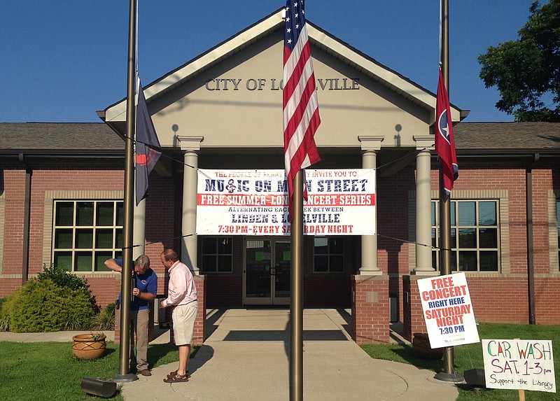 Lobelville Mayor Robby J. Moore, right, and business owner Robert Mathis lower flags in front of City Hall in Lobelville, Tenn., on July 10, 2014. A 15-year-old was charged with one count of criminal homicide in the fatal shooting of a longtime member of the National Guard at a Tennessee armory, according to the state's Bureau of Investigation. 
            