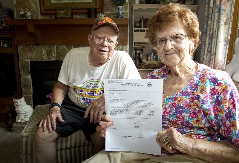 
              In this photo taken on Tuesday, July 8, 2014, Harold Weaver sits behind his wife, Martha, in their Nickleville, Pa, home. Martha holds a letter from the Selective Service for her late father, Fred Minnick, requiring him to register for the nation's military draft. The letter arrived too late for Minnick, who was born in 1894 and died on April 20, 1992. (AP Photo/The Derrick, Jerry Sowden)
            