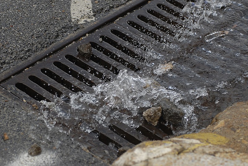 Water flows into a storm drain at the corner of Main Street and Mitchell Avenue.