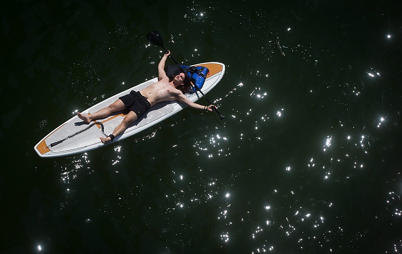 A man soaks up the sunshine Sunday as he lies on a paddleboard floating on False Creek in Vancouver, British Columbia. According to Environment Canada, Sunday was set to be the peak of temperatures during a current hot spell. Highs of 81 degrees were forecast for Vancouver.    (AP Photo/The Canadian Press, Darryl Dyck)