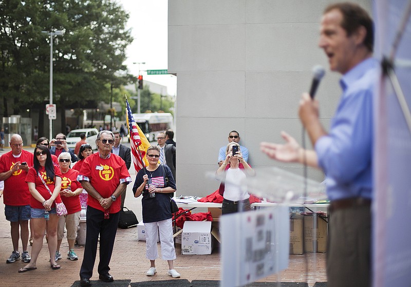 
              Demonstrators look on as Americans for Prosperity President Tim Phillips, right, speaks out against tougher pollution restrictions at a rally in response to an Environmental Protection Agency hearing, Tuesday, July 29, 2014, in Atlanta. Utility and coal companies are expected to argue Tuesday against proposals from the Obama administration that would force a 30 percent cut in carbon dioxide emissions by the year 2030 from 2005 levels. The EPA is holding three public hearings on the proposal in Atlanta, Denver and Washington. (AP Photo/David Goldman)
            
