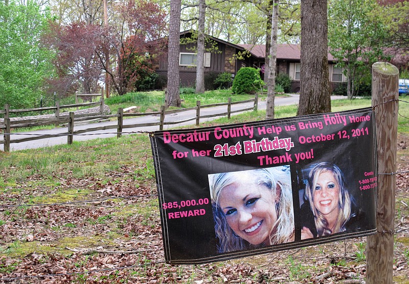 In this 2014 file photo, a poster with pictures of missing Tennessee nursing student Holly Bobo hangs on a fence in front of her house in Parsons, Tenn.