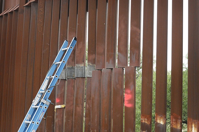 
              A repair crew's ladder leans against a section of the border fence under repair near Nogales, Ariz., Sunday, July 27, 2014, after suspected smugglers made a garage-sized hole in the steel barrier that divides the U.S. and Mexico. It was one of two incidents this past weekend that left parts of the fence down after floods from rainstorms knocked down a 60-feet stretch of fence. (AP Photo/Nogales International, Curt Prendergast)
            