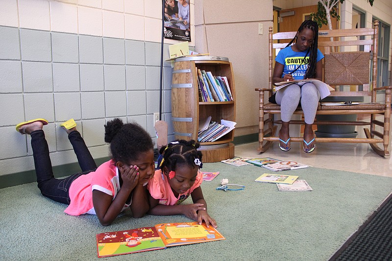 Tamika Burks, right, fills out forms as her daughter, Gezelle Champion, center, and her stepdaughter, Jada Champion, read in the lobby of H.H. Battle Elementary during Registration day for Hamilton County public schools Monday. Burks came to register 6-year-old Gezelle, and her 9-year-old son, Aurello Ramsey Jr., not pictured, for the elementary school.