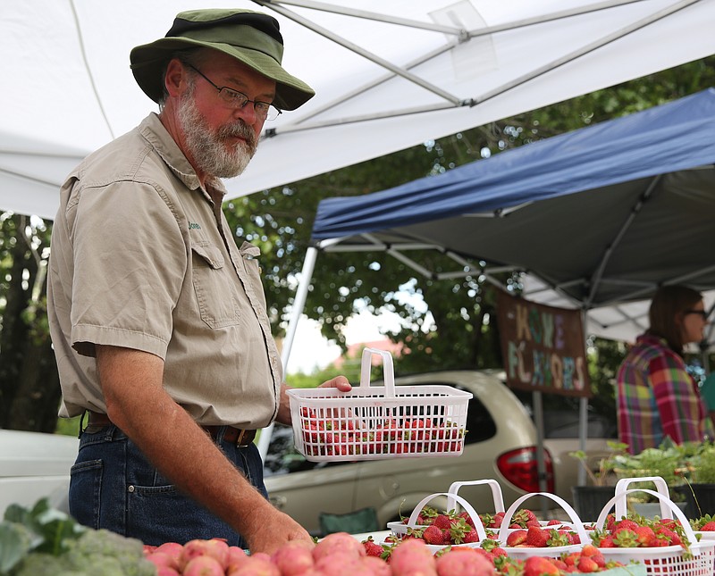 Roy Jones, the owner of Jones Farm, organizes baskets of strawberries at his booth at the grand opening of the St. Elmo's Farmers' Market in May.