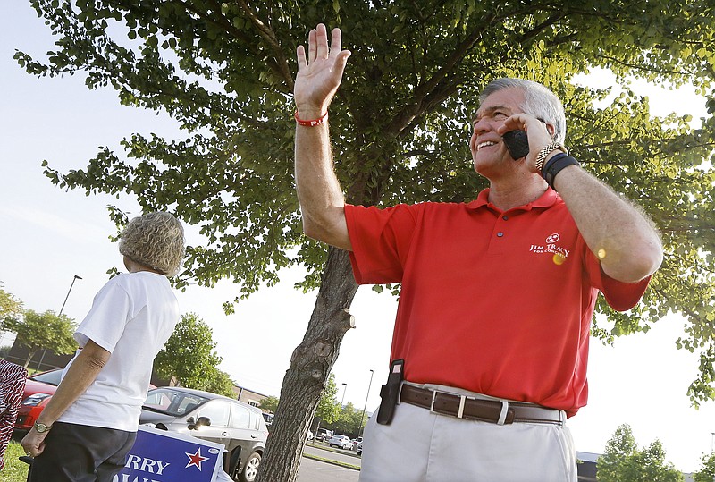 State Sen. Jim Tracy, R-Shelbyville, talks on the phone and waves at cars at a polling place as he campaigns for Congress on Thursday in Murfreesboro, Tenn.