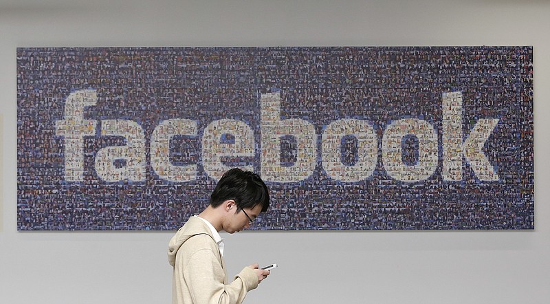 
              FILE - In this June 11, 2014 photo, a man walks past a Facebook sign in an office on the Facebook campus in Menlo Park, Calif. Facebook’s recent effort to force people to adopt its standalone mobile messaging app has privacy-concerned users up in arms. In truth, Facebook Messenger isn’t any more invasive than Facebook’s main app _or other similar applications. (AP Photo/Jeff Chiu, File)
            