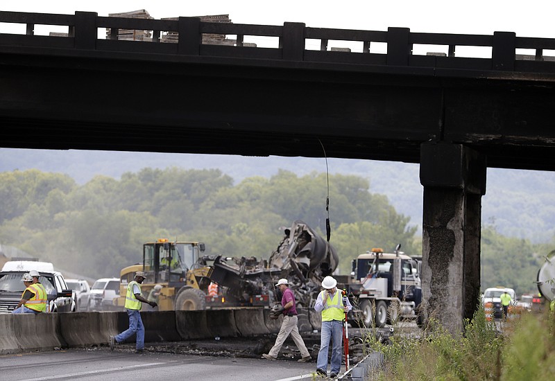 
              Emergency personnel work under an overpass blackened from a fire where a gasoline tanker truck exploded and burned after hitting the overpass on Interstate 65 near Franklin, Tenn., Friday Aug. 15, 2014. Officials said the driver of the truck, working for the Edwards Oil Co. of Lawrenceburg, was killed. (AP Photo/Mark Humphrey)
            