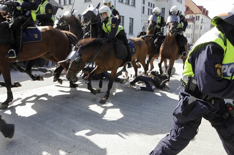 
              Police mounted on horses ride through counter-demonstrators protesting against an election meeting arranged by the neo-nazi party "Svenskarnas Parti", at a square in central Malmo, Sweden, Saturday, Aug. 23, 2014. Two people were reportedly injured. There were several thousand protesters, while the party meeting totaled less than a hundred sympathizers. (AP Photo/TT News Agency, Drago Prvulovic)   SWEDEN OUT
            