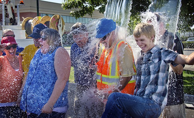 
              In this photo taken on Tuesday, Aug. 26, 2014, Ten Pocket iNet corporation employees, from left,including Terri McMakin, Don Gibbard, weargin hard hat, and Jake Tegtmeier, right, take the ice bucket challenge at the Walla Walla Regional Airport in Walla Walla, Wash.to benefit ALS research. The water was poured from two lift trucks. Gibbard said he wore his hard hat to protect from the ice cubes and took the brunt of dousing because "I was pulled back!" (AP Photo/Walla Walla Union-Bulletin, Greg Lehman)
            