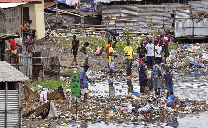 
              People stand on the shoreline near a sign reading 'NO DUMPING', amongst rubbish at West Point, a area heavily effected by the  Ebola virus, with residence not being  allowed to leave West Point,  as government forces clamp down on movement to prevent the spread of Ebola, in  Monrovia, Liberia, Wednesday, Aug. 27, 2014. Health officials in Liberia said the other two recipients of ZMapp in Liberia — a Congolese doctor and a Liberian physician's assistant, have recovered. Both are expected to be discharged from an Ebola treatment center on Friday, said Dr. Moses Massaquoi, a Liberian doctor with the treatment team. (AP Photo/Abbas Dulleh)
            