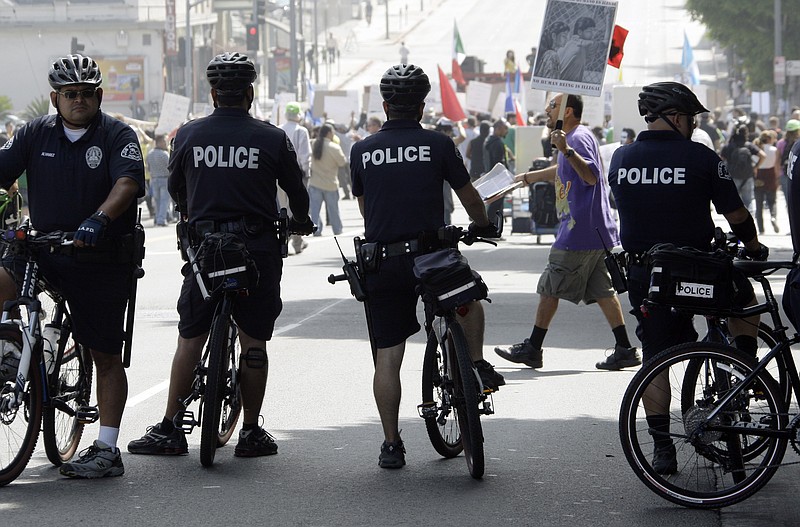 
              FILE - In this Sept. 18, 2010 file photo, officers on bicycles keep watch as demonstrators protesting several incidents of alleged Los Angeles Police Department brutality, including the fatal shooting of Manuel Jamines a month ago, stand outside the LAPD's Rampart Station in the Westlake district of Los Angeles. Police departments across the U.S. are using technology to try to identify problem officers before their misbehavior harms innocent people, embarrasses their employer, or invites a costly lawsuit,  from citizens or the federal government.  The Los Angeles Police Department agreed to set up their $33 million early warning systems after the so-called Rampart scandal in which an elite anti-gang unit was found to have beaten and framed suspected gang members. The system was then implemented in 2007. (AP Photo/Reed Saxon)
            