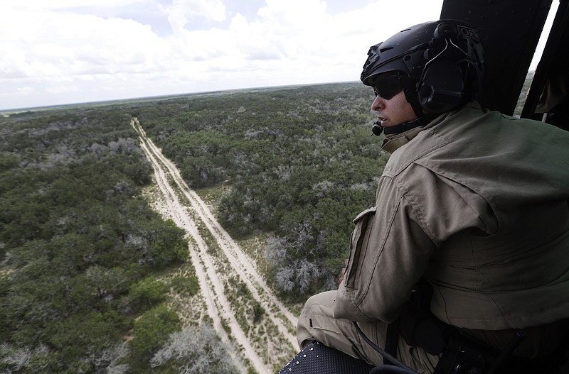 
              In this Sept. 5, 2014 photo, a U.S. Customs and Border Protection Air and Marine agent pears out of the open door of a helicopter during a patrol flight near the Texas-Mexico border near McAllen, Texas. Since illegal immigration spiked in the Rio Grande Valley this summer, the Border Patrol has dispatched more agents, the Texas Department of Public Safety has sent more troopers and Texas Gov. Rick Perry deployed as many as 1,000 guardsmen to the area. (AP Photo/Eric Gay)
            