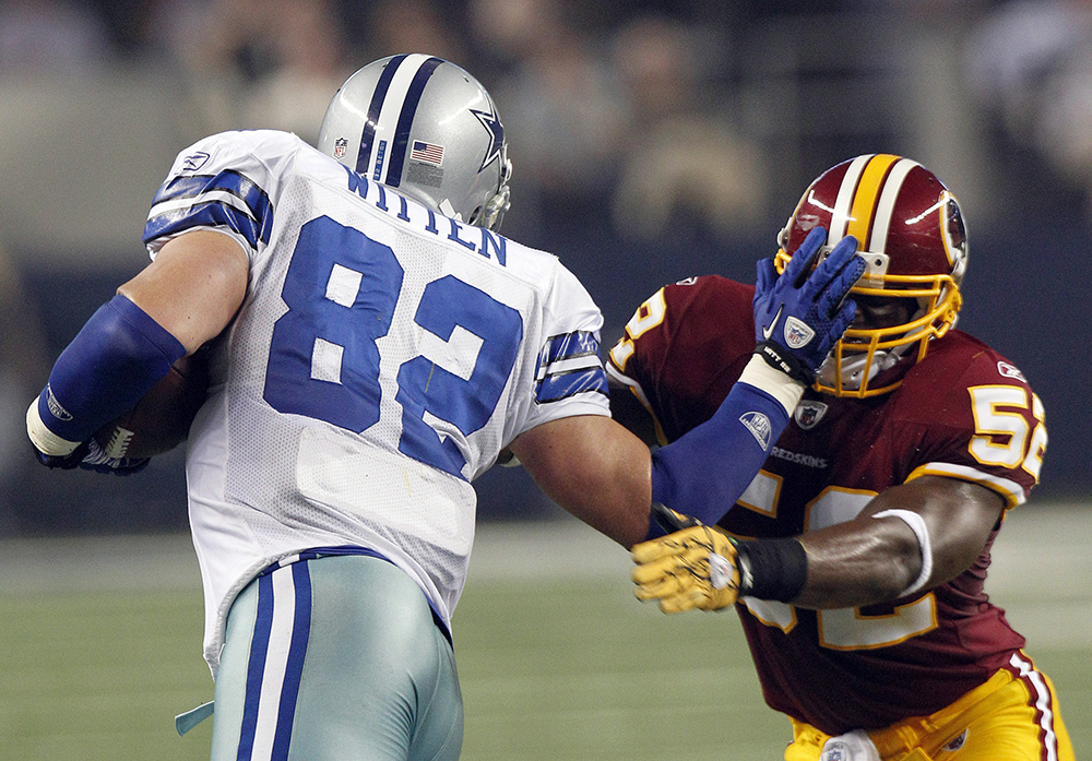 Dallas Cowboys tight end Jason Witten (82) stiff arms Washington Redskins  strong safety DeJon Gomes (24) on a 4-yard pass play in the third quarter  at Cowboys Stadium in Arlington, Texas, on Thanksgiving Day, Thursday,  November 22, 2012. The