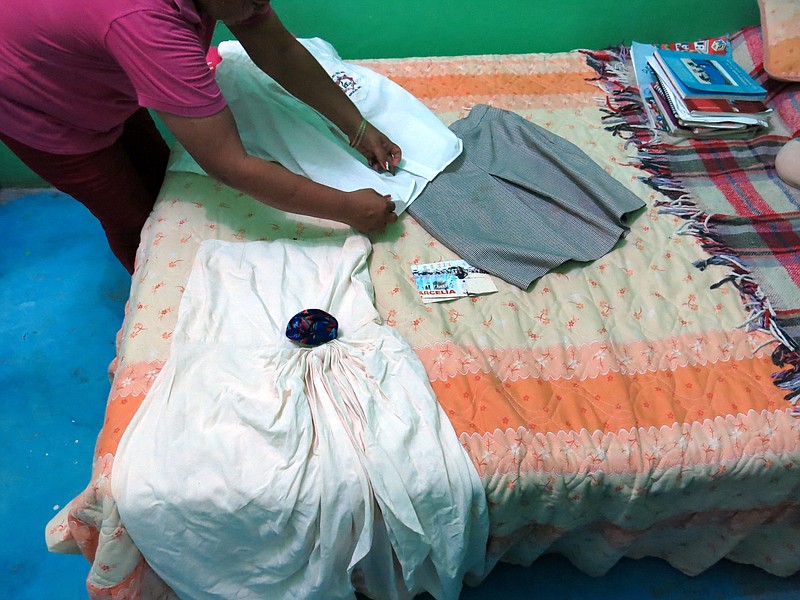 
              In this Sept. 15, 2014 photo, a woman who did not want to give her name for fear of reprisals, lays out the clothes of her late 15-year-old daughter Erika Gomez Gonzalez, on a bed at her home in Arcelia, Mexico. The woman says she witnessed her child's death when army soldiers fired first at an armed group at a grain warehouse on June 30 in the town of San Pedro Limon, Mexico. She said one man died in the initial shootout, when the rest of the gunmen surrendered on the promise they would not be hurt. She recalls that her daughter, who was face down in the ground with a bullet in her leg, was rolled over while she was still alive and shot more than half a dozen times in the chest. The mother said she arrived to the warehouse the day before the shooting, in an attempt to take her daughter home, but gang members wouldn't let her. (AP Photo/Eduardo Castillo)
            